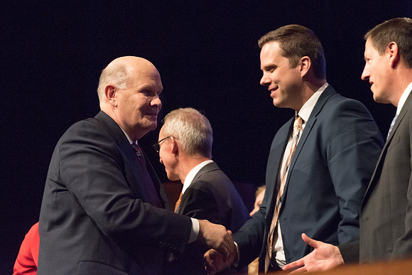 Elder Renlund shakes the hands of and greets those who sit on the stand at the end of his devotional address. 2017