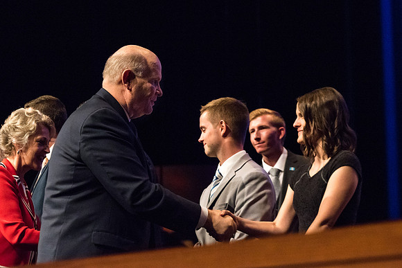 Elder Renlund shakes the hands of and greets those who sit on the stand at the end of his devotional address. 2017