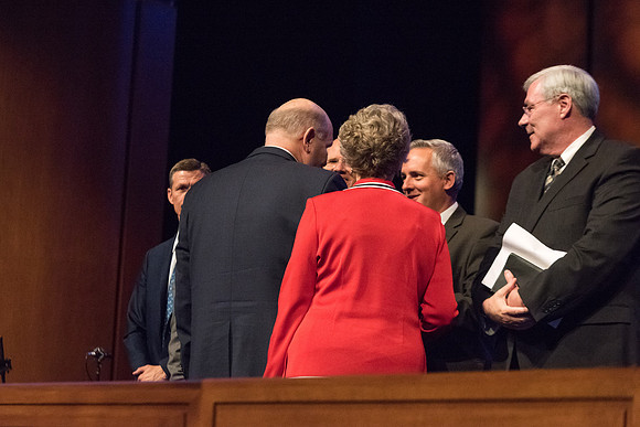 Elder Renlund shakes the hands of and greets those who sit on the stand at the end of his devotional address. 2017