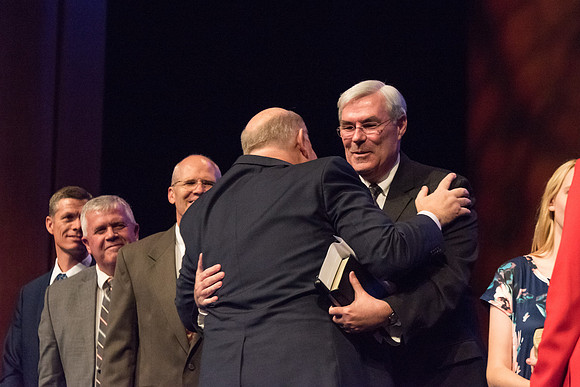 Elder Renlund shakes the hands of and greets those who sit on the stand at the end of his devotional address. 2017