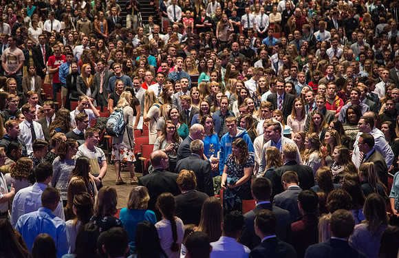 Students stand out of respect and look on as Elder Dale G. Renlund makes his way through the audience shaking hands before the start of devotional.