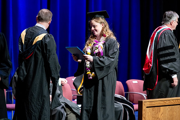 Graduates of the Performing and Visual Arts walk across the stage and accept their diplomas.