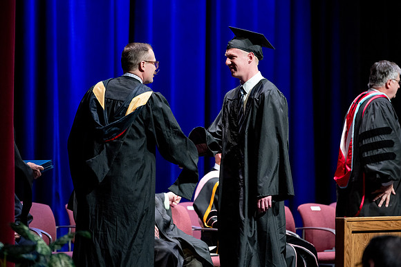 Graduates of the Performing and Visual Arts walk across the stage and accept their diplomas.