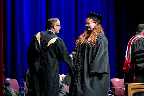 Graduates of the Performing and Visual Arts walk across the stage and accept their diplomas.