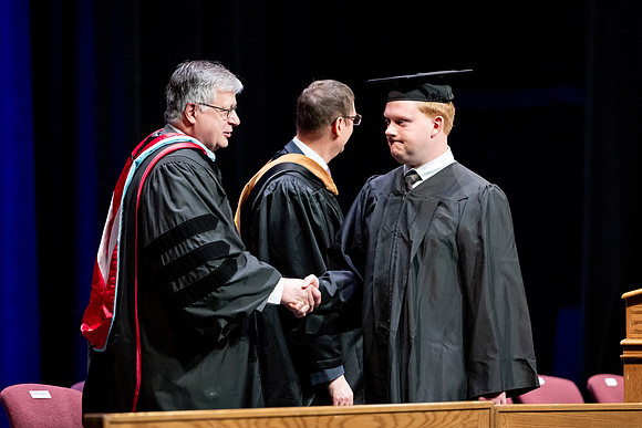 Graduates of the Performing and Visual Arts walk across the stage and accept their diplomas.