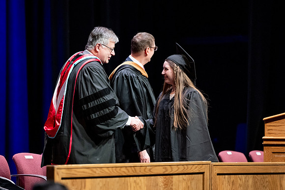 Graduates of the Performing and Visual Arts walk across the stage and accept their diplomas.