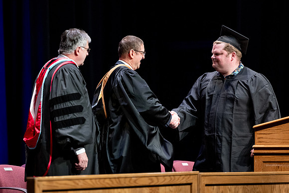 Graduates of the Performing and Visual Arts walk across the stage and accept their diplomas.