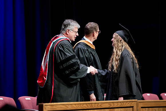 Graduates of the Performing and Visual Arts walk across the stage and accept their diplomas.