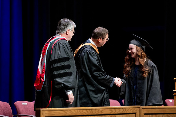 Graduates of the Performing and Visual Arts walk across the stage and accept their diplomas.
