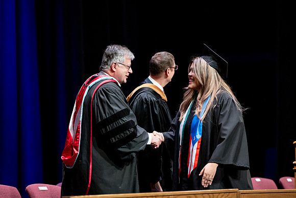 Graduates of the Performing and Visual Arts walk across the stage and accept their diplomas.