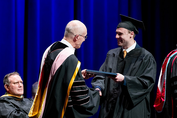 Graduates of the Performing and Visual Arts walk across the stage and accept their diplomas.
