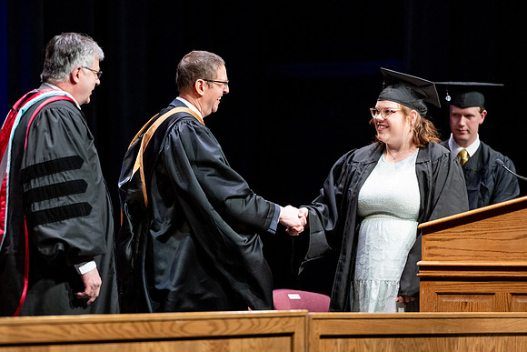 Graduates of the Performing and Visual Arts walk across the stage and accept their diplomas.