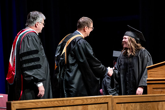 Graduates of the Performing and Visual Arts walk across the stage and accept their diplomas.