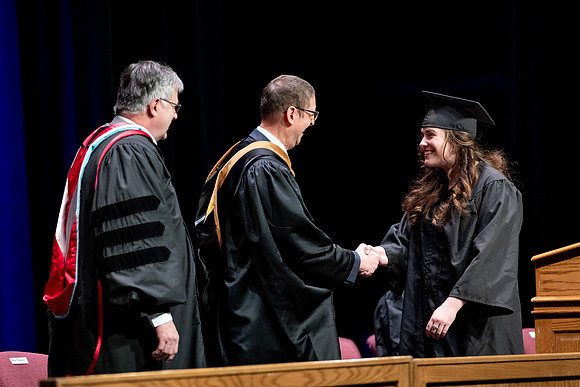 Graduates of the Performing and Visual Arts walk across the stage and accept their diplomas.