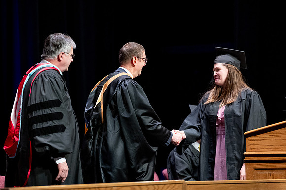 Graduates of the Performing and Visual Arts walk across the stage and accept their diplomas.