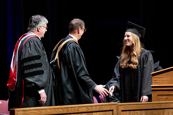 Graduates of the Performing and Visual Arts walk across the stage and accept their diplomas.