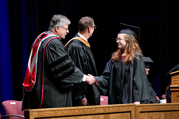 Graduates of the Performing and Visual Arts walk across the stage and accept their diplomas.