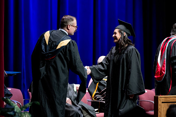 Graduates of the Performing and Visual Arts walk across the stage and accept their diplomas.