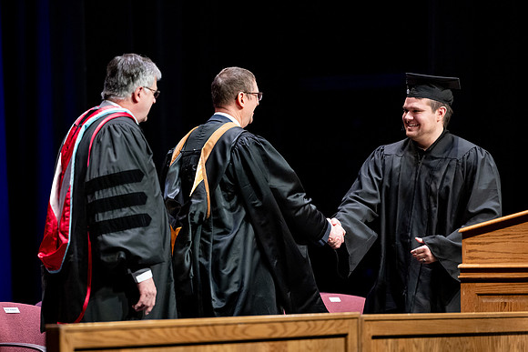 Graduates of the Performing and Visual Arts walk across the stage and accept their diplomas.