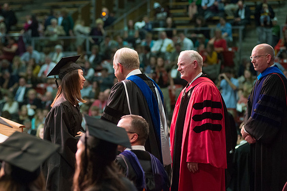 Elder W. Craig Zwick and President Kim B. Clark award diploma covers to graduates in the College of Business and Communication.