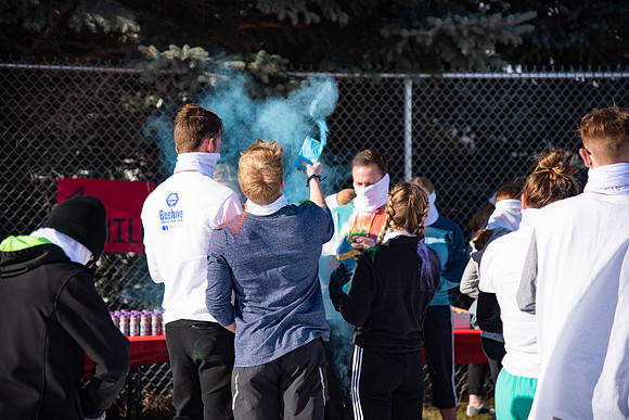 Students and their families throwing colored chalk before the race starts.