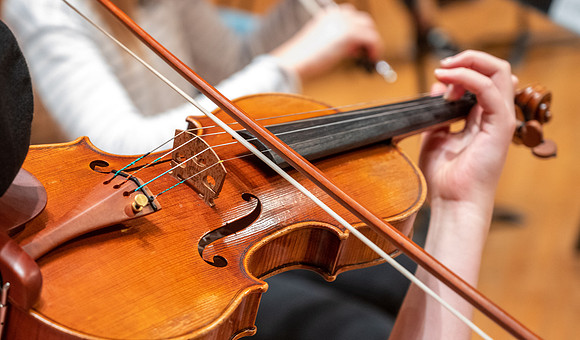 String instruments practice in the Barrus Concert Hall under the direction of Robert Tueller.