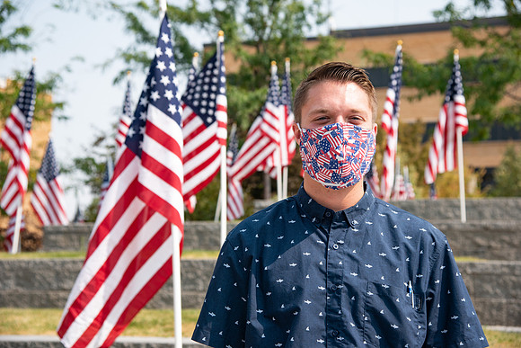 Student wearing an American flag face mask with multiple flags behind him.
