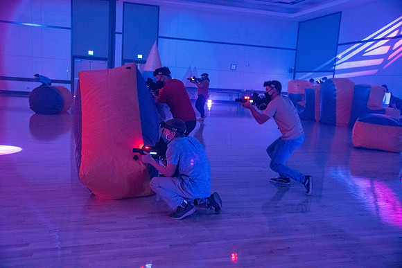 Students play laser tag on campus with masks on.