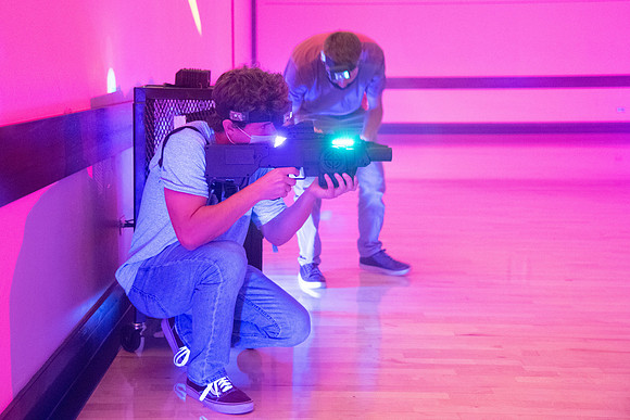 Students play laser tag on campus with masks on.
