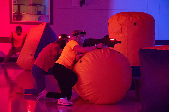 Students play laser tag on campus with masks on.