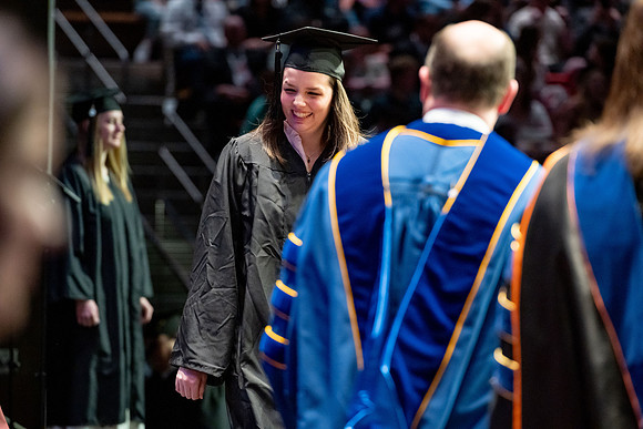Graduates walk across the stage.