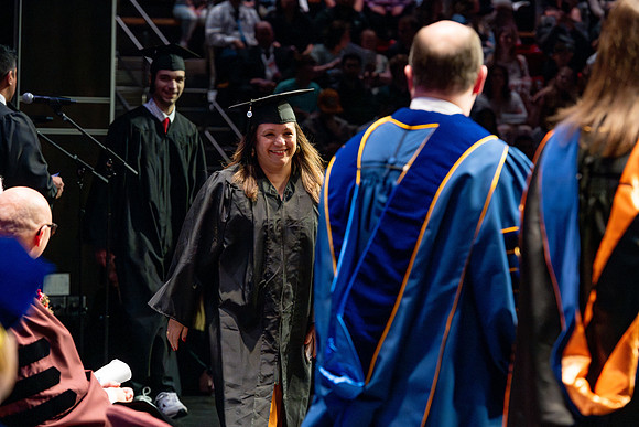 Graduates walk across the stage.