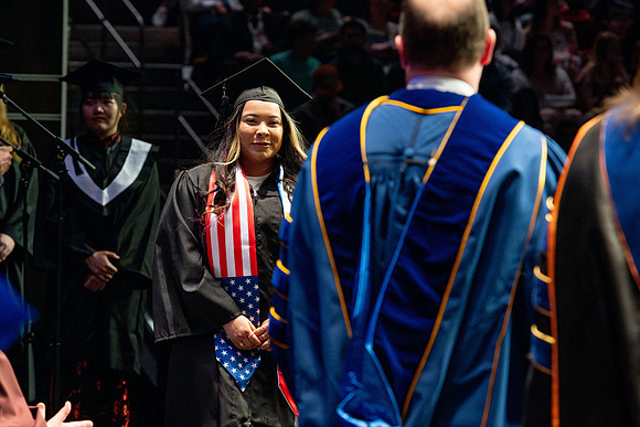 Graduates walk across the stage.