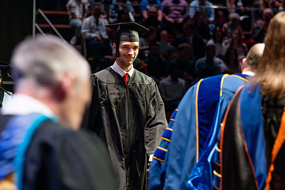 Graduates walk across the stage.