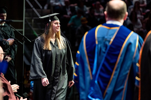 Graduates walk across the stage.
