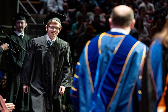 Graduates walk across the stage.