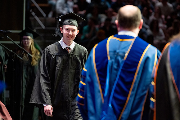 Graduates walk across the stage.