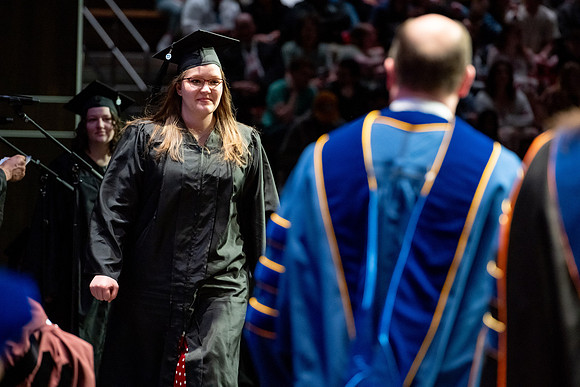 Graduates walk across the stage.