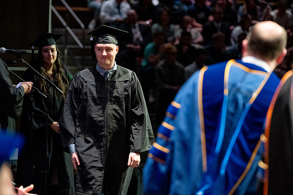 Graduates walk across the stage.