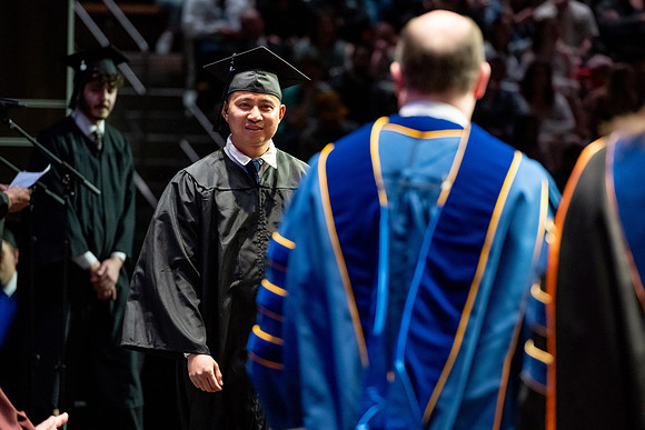 Graduates walk across the stage.