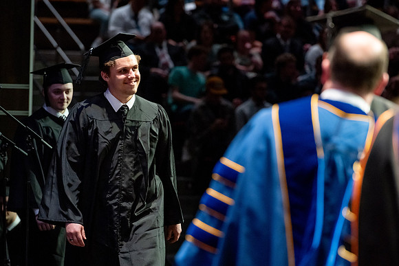 Graduates walk across the stage.