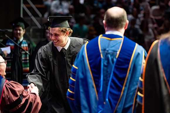 Graduates walk across the stage.