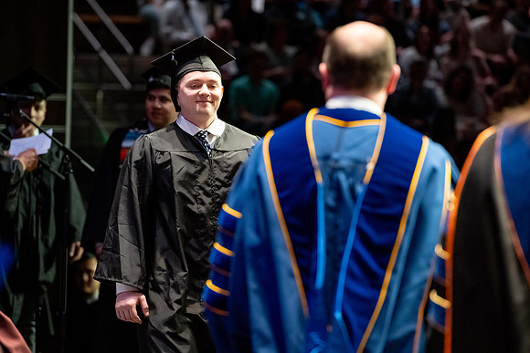 Graduates walk across the stage.