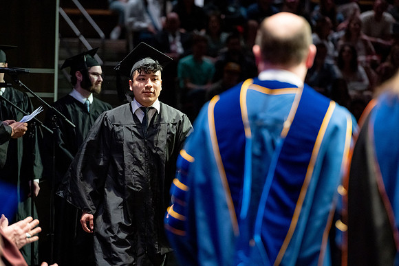 Graduates walk across the stage.