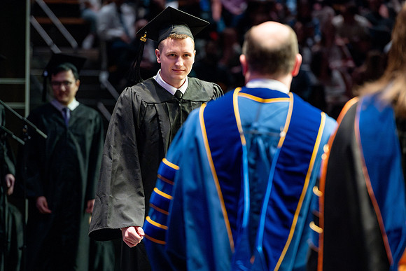 Graduates walk across the stage.