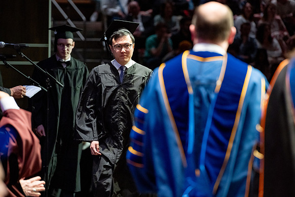Graduates walk across the stage.