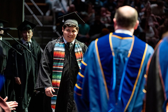 Graduates walk across the stage.