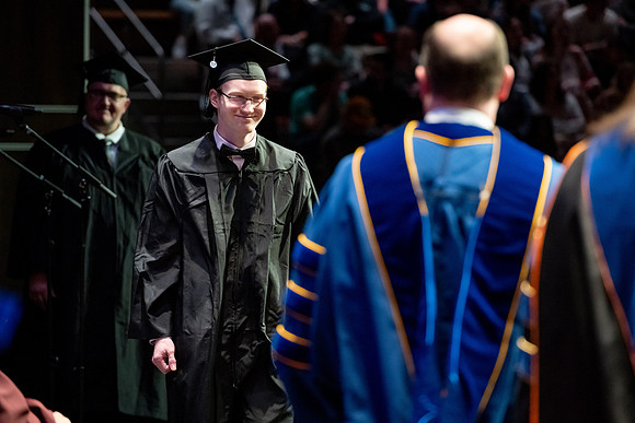 Graduates walk across the stage.