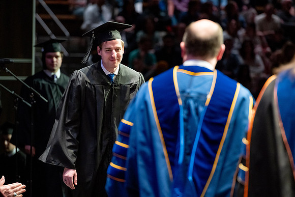 Graduates walk across the stage.