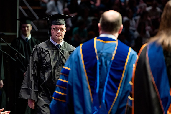 Graduates walk across the stage.